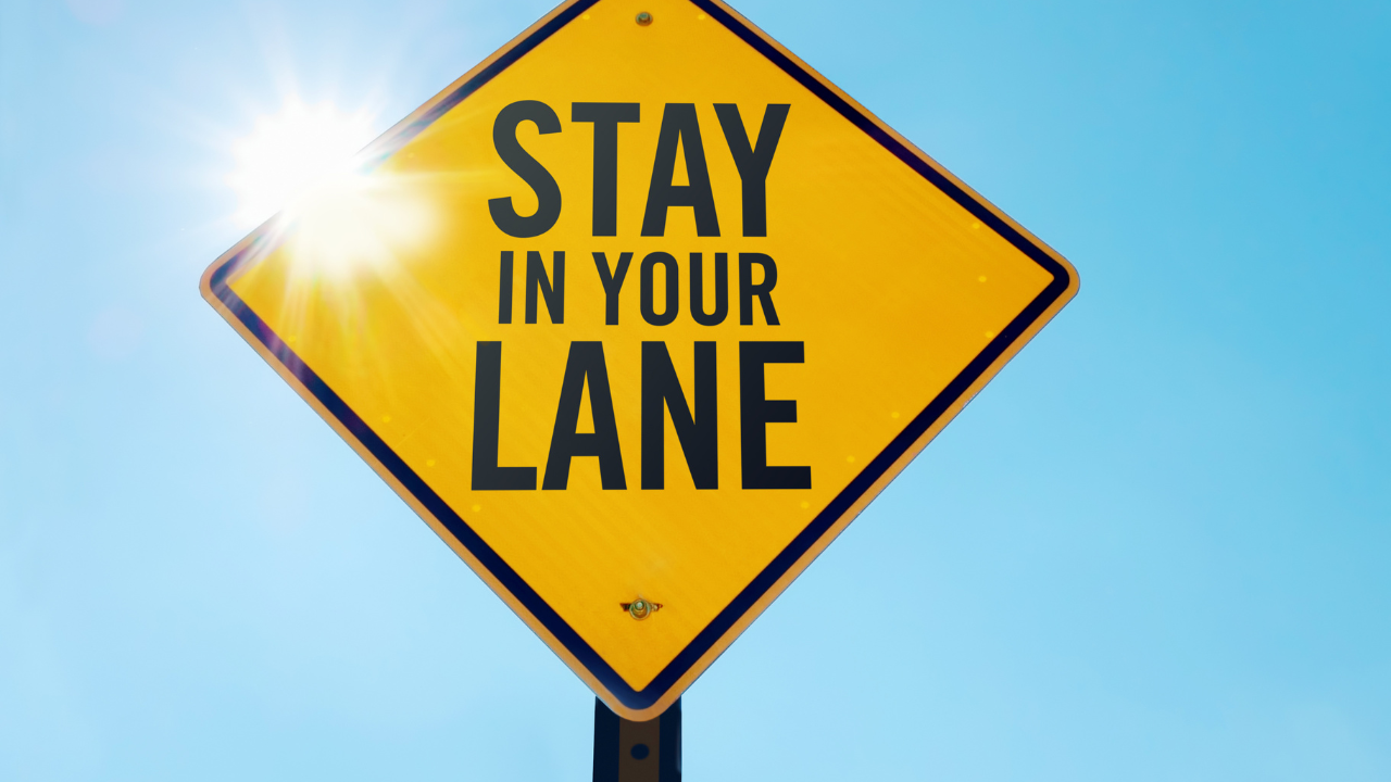 Road sign reading "Stay in Your Own Lane," symbolizing how to stay on track in business and avoid distractions.